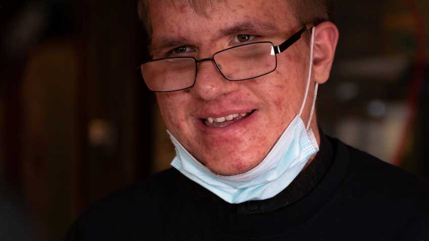 A mean wears glasses and has a covid mask under his chin