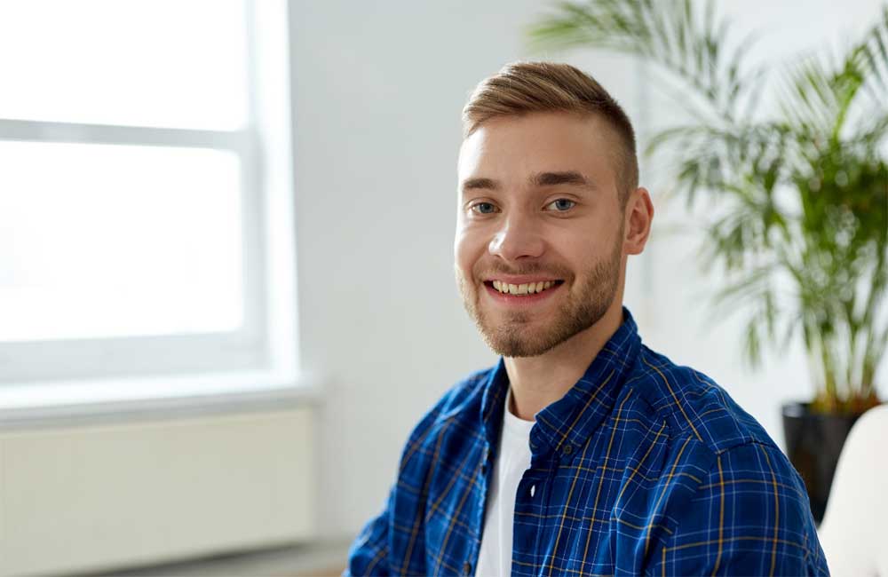 A young man with beard smiling looking at camera